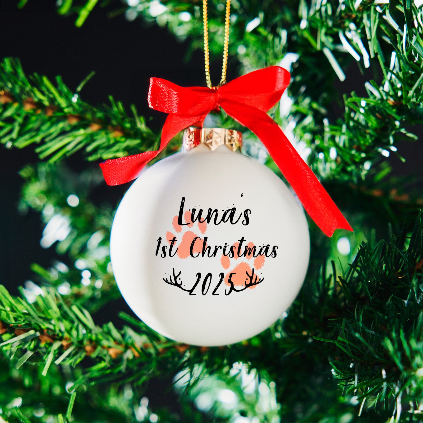 Personalised pet’s first Christmas bauble with paw prints and red bow on Christmas tree – dog or cat ornament 2025
